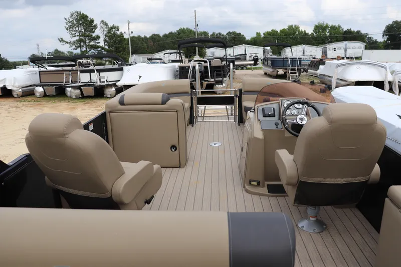 Slide: The Image of 2024 Starcraft 24 EX QDH pontoon boat interior with beige seating and steering console. - 9