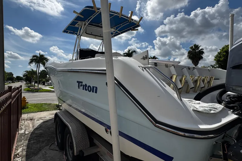 Slide: The Image of 2003 Triton 2895 CC boat on trailer under a partly cloudy sky. - 13