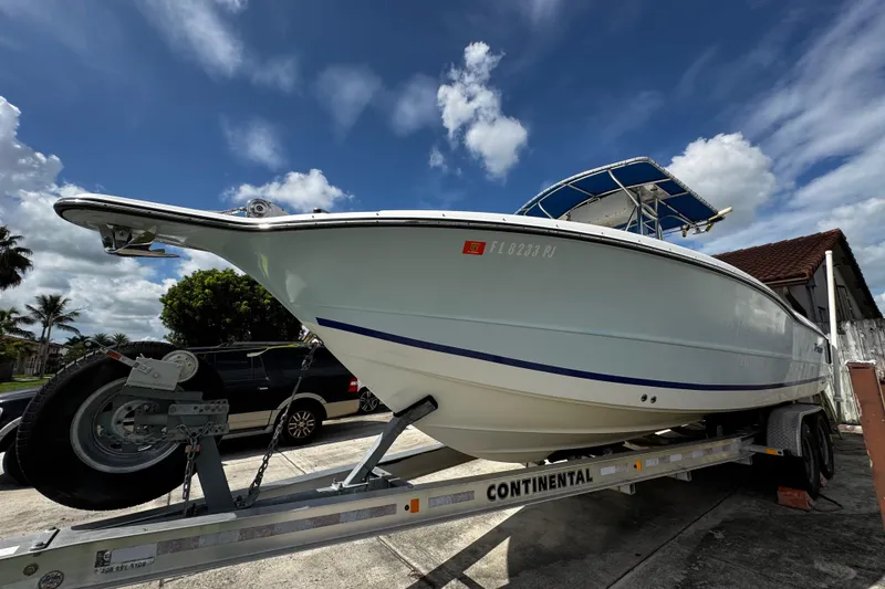 Slide: The Image of 2003 Triton 2895 CC boat on trailer under a partly cloudy sky. - 15