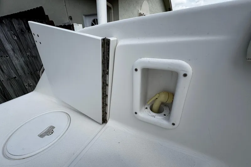 Slide: The Image of 2003 Triton 2895 CC boat deck with storage compartment and hose connection. - 21