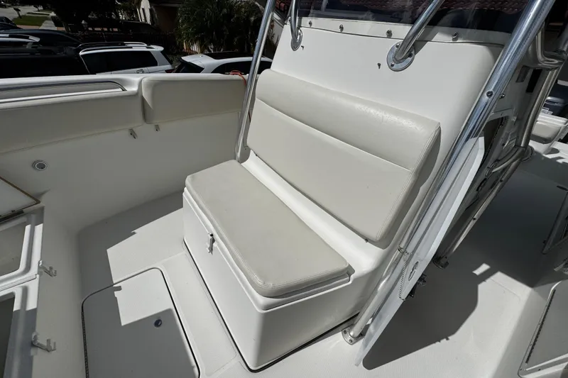 Slide: The Image of 2003 Triton 2895 CC boat seating area with cushioned bench and storage. - 54