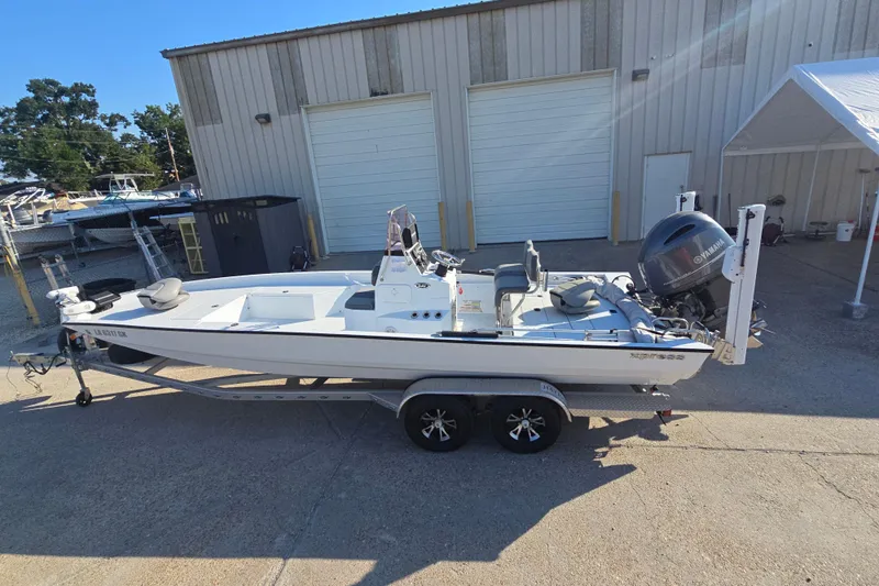 Slide: The Image of 2019 Xpress H24B boat on trailer, parked outside a warehouse. - 6