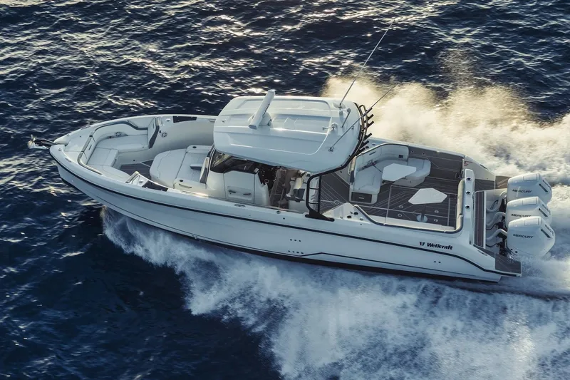 Slide: The Image of 2026 Wellcraft 38 T-Top boat interior with white seating, docked near other boats. - 21