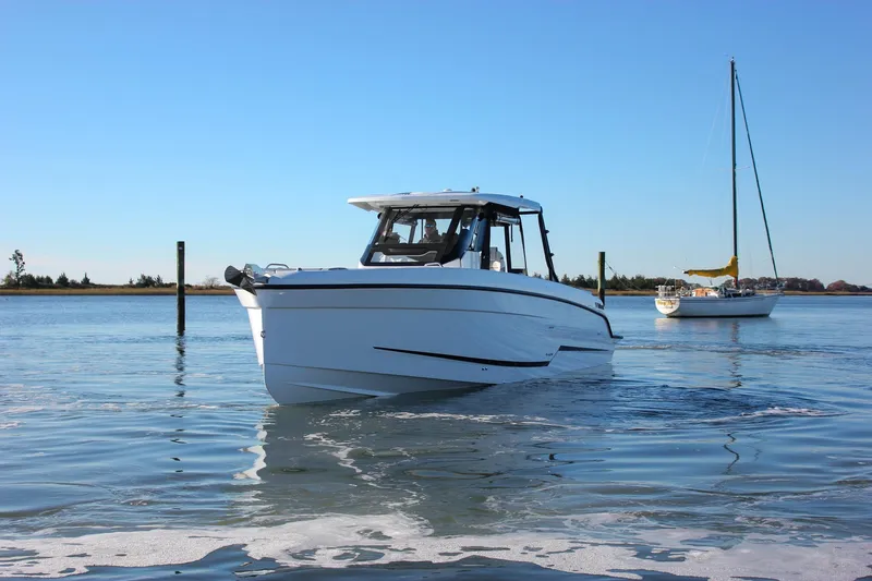 Slide: The Image of 2026 Wellcraft 38 T-Top boat cruising on calm water with sailboat in background. - 30