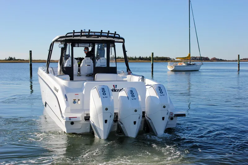 Slide: The Image of 2026 Wellcraft 38 T-Top boat on calm water with sailboat in background. - 32