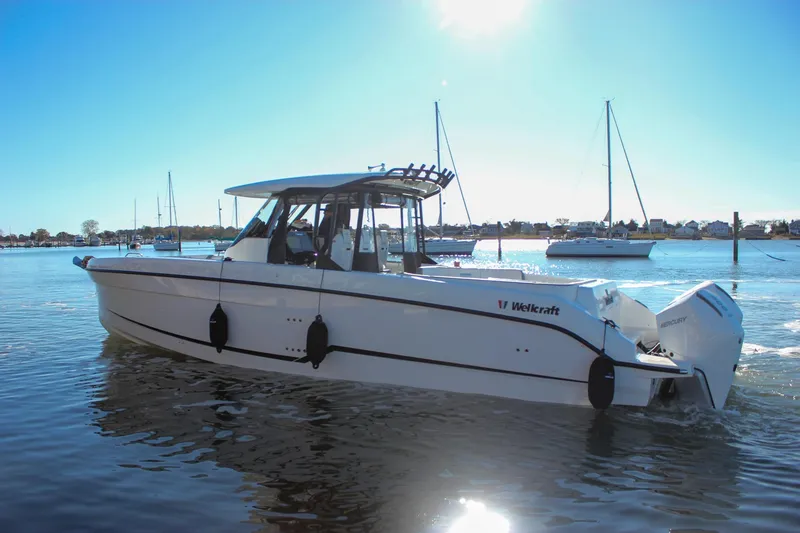 Slide: The Image of 2026 Wellcraft 38 T-Top boat cruising on calm waters under clear blue sky. - 33