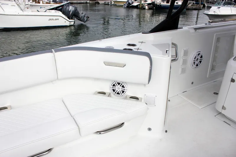 Slide: The Image of 2026 Wellcraft 38 T-Top boat interior with white seating and speakers at a marina. - 51