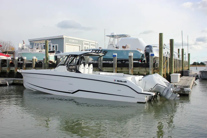 Slide: The Image of 2026 Wellcraft 38 T-Top boat docked at a marina with outboard engines. - 64