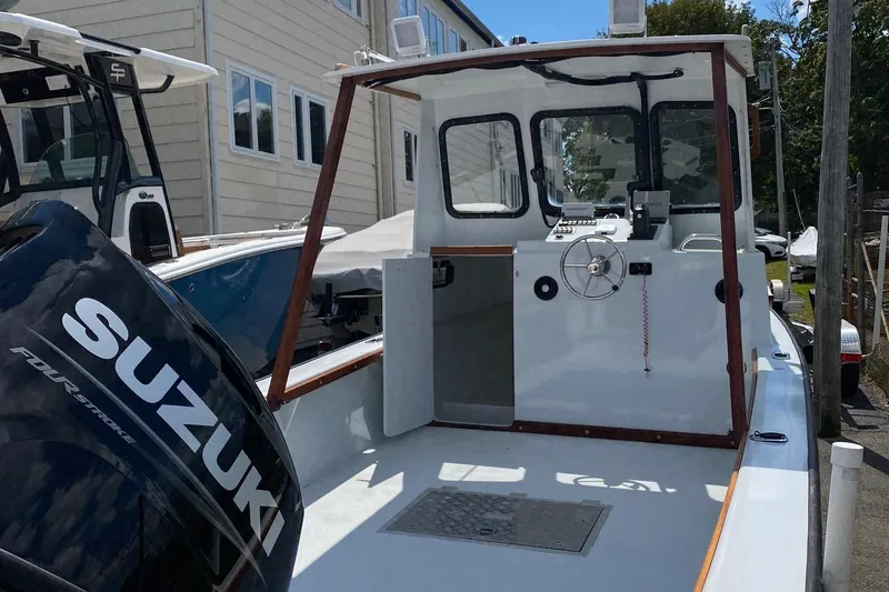 Slide: The Image of 1991 Eastern Lobsterman boat with Suzuki outboard motor, docked near a building. - 3