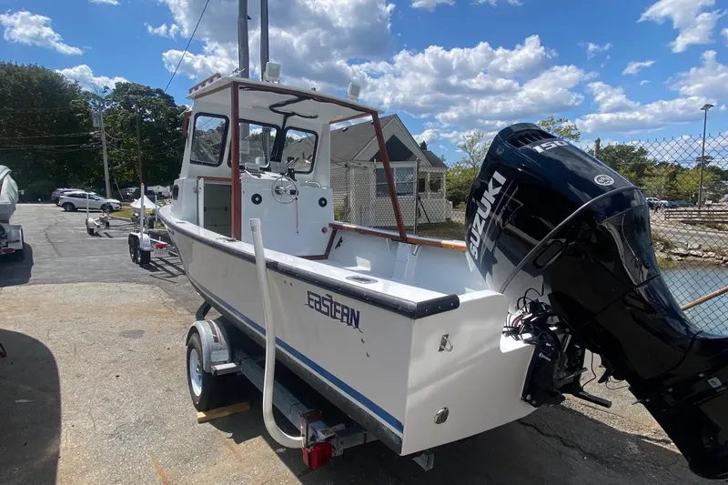 Slide: The Image of 1991 Eastern Lobsterman boat with Suzuki engine on trailer, parked outdoors under blue sky. - 2