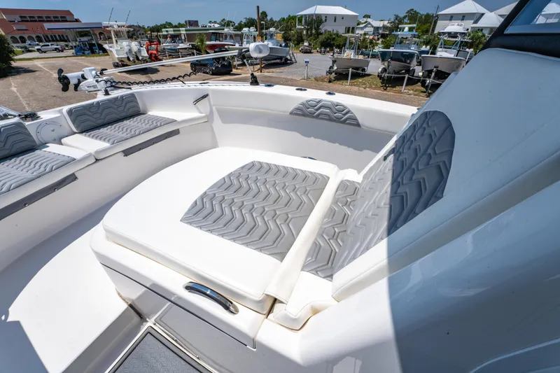 Slide: The Image of 2022 Twin Vee 280 GFX CC boat with cushioned seating in a marina setting. - 14