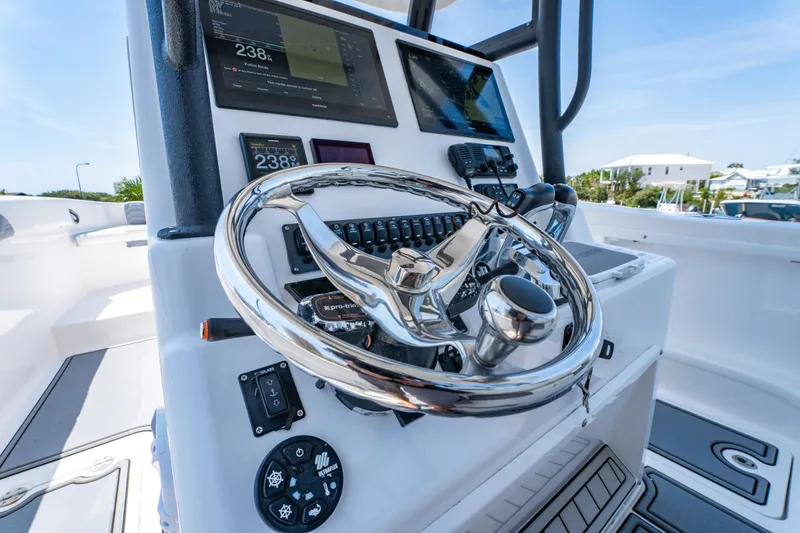 Slide: The Image of 2022 Twin Vee 280 GFX CC boat dashboard with steering wheel and navigation displays. - 22