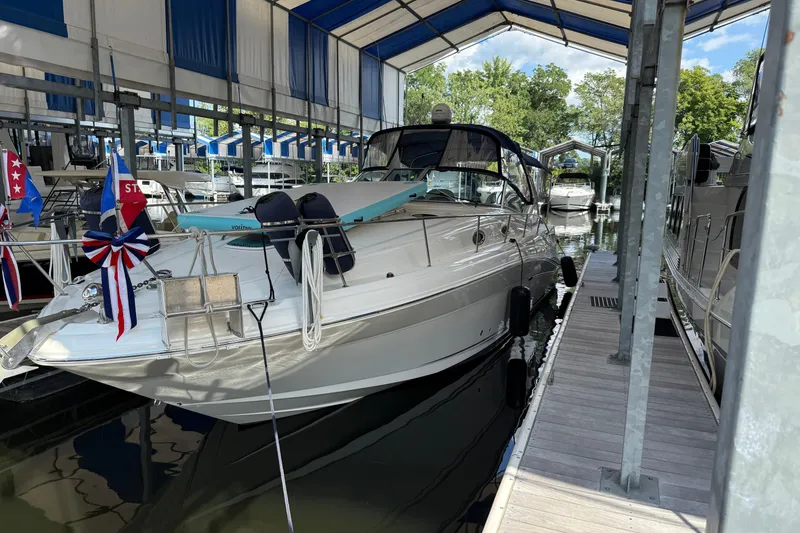 Slide: The Image of 2006 Sea Ray 340 Sundancer docked under a covered marina with decorative flags. - 1