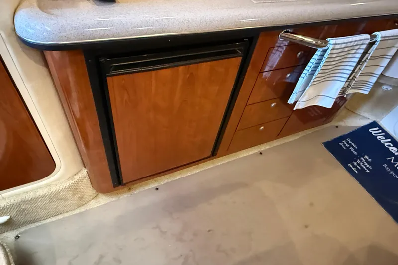 Slide: The Image of 2006 Sea Ray 340 Sundancer interior with wooden cabinetry and compact refrigerator. - 11