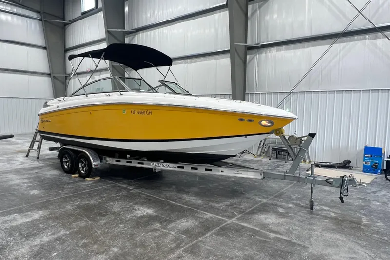 Slide: The Image of 2006 Cobalt 232 boat with yellow hull on trailer in indoor storage. - 2