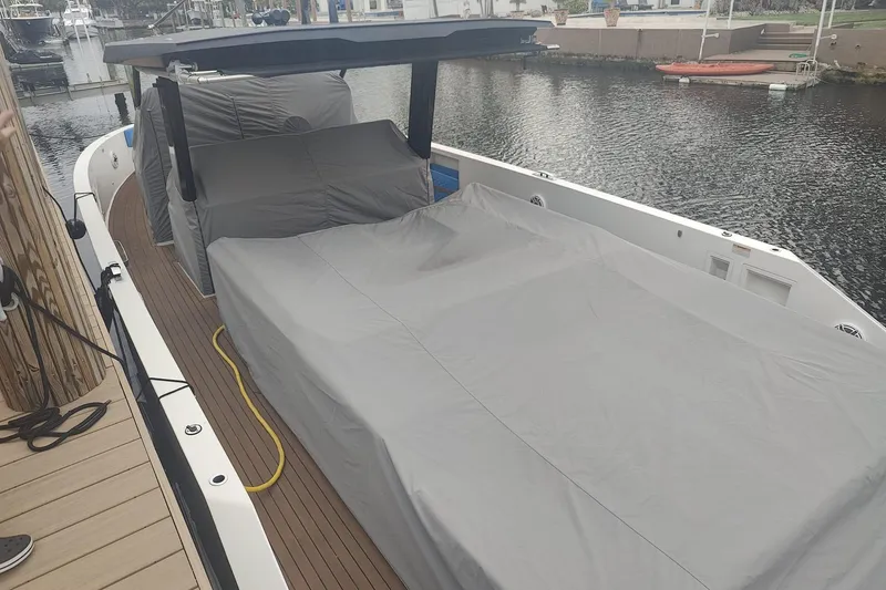Slide: The Image of 2021 De Antonio Yachts Center Console covered, docked by a calm waterfront. - 24