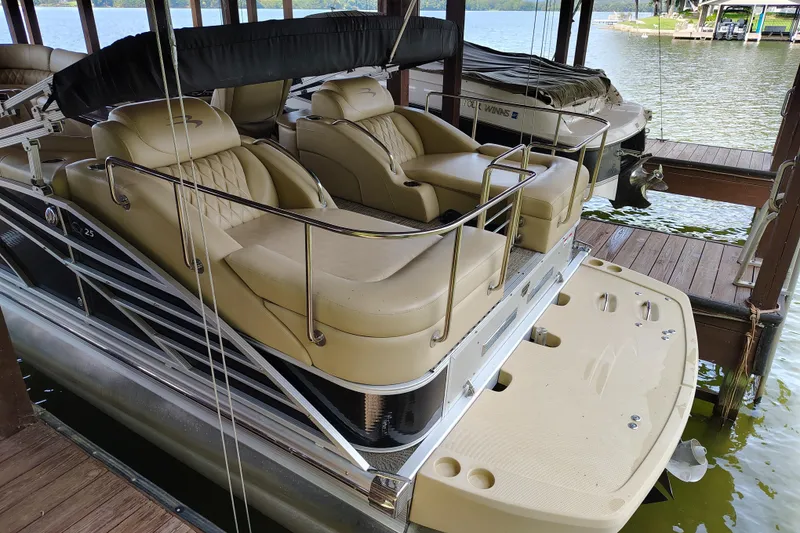 Slide: The Image of 2014 Bennington 2575 QCW I/O pontoon boat docked, featuring luxurious seating and sleek design. - 11