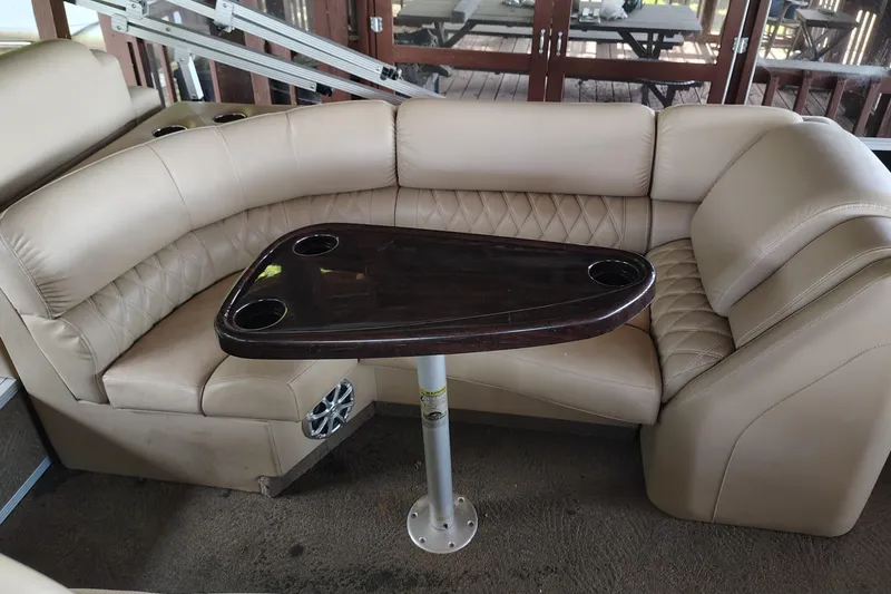 Slide: The Image of 2014 Bennington 2575 QCW I/O boat interior with beige seating and dark wood table. - 24