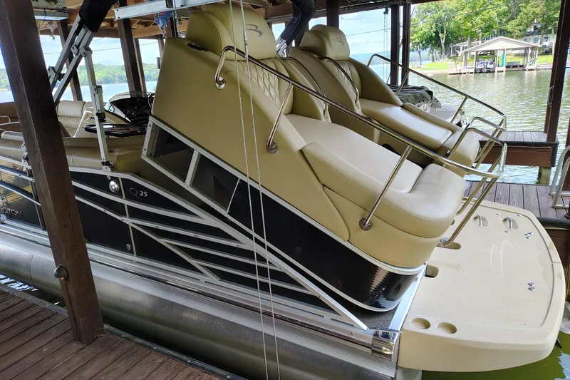 Slide: The Image of 2014 Bennington 2575 QCW I/O pontoon boat docked, featuring luxurious seating and sleek design. - 38