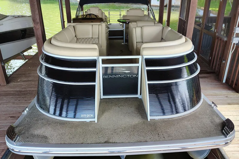 Slide: The Image of 2014 Bennington 2575 QCW I/O pontoon boat with luxurious seating, docked in a covered area. - 4