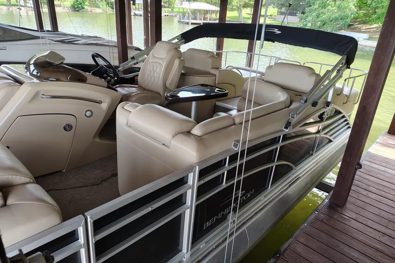 Slide: The Image of 2014 Bennington 2575 QCW I/O pontoon boat docked, featuring luxurious beige seating. - 8
