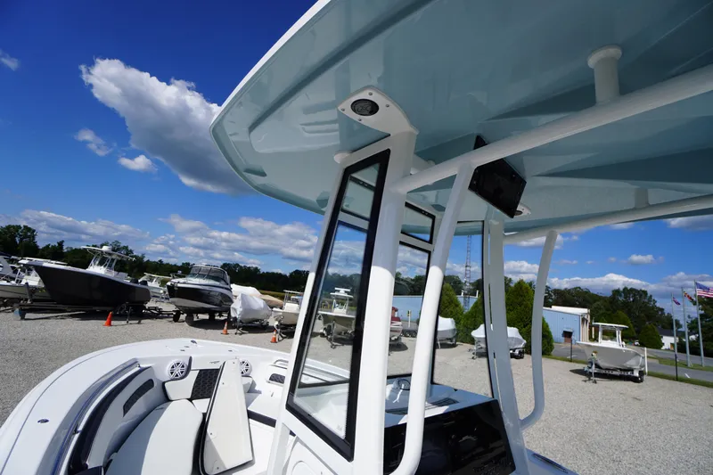 Slide: The Image of 2026 Tidewater 220 LXF boat with T-top, parked outdoors under a clear blue sky. - 21