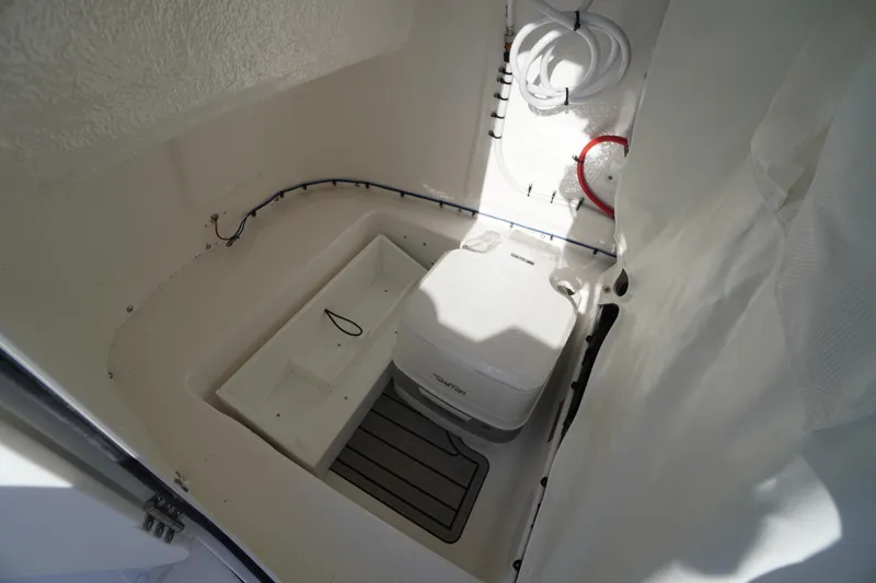 Slide: The Image of 2026 Tidewater 220 LXF boat interior with compact marine toilet and storage. - 29
