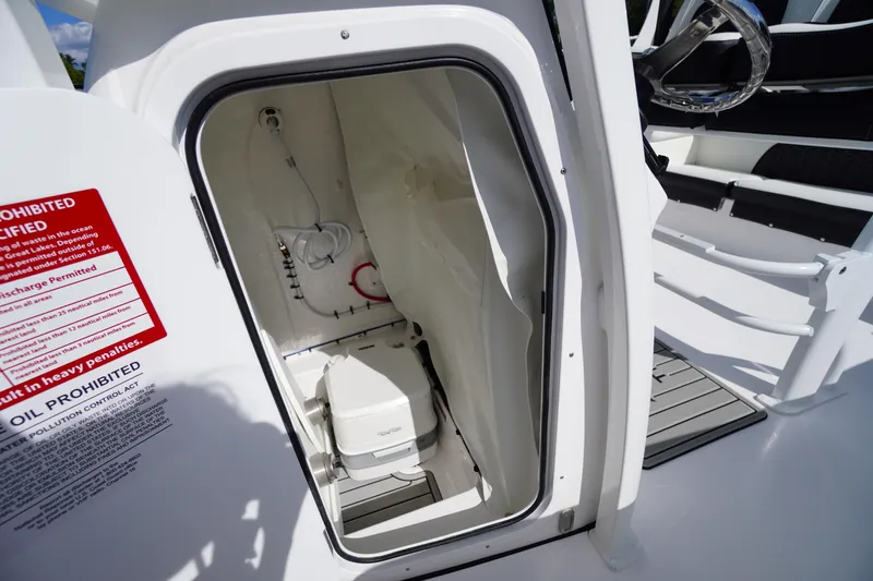Slide: The Image of 2026 Tidewater 220 LXF boat interior with compact marine toilet and storage area. - 31