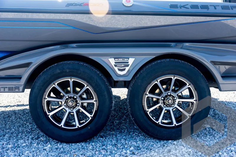 Slide: The Image of 2026 Skeeter FXR21 Apex boat trailer with dual wheels on gravel surface. - 28
