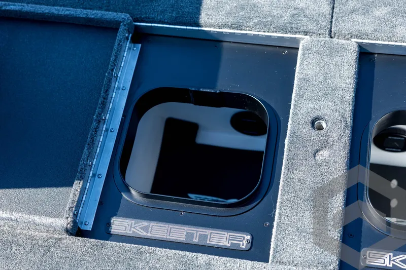Slide: The Image of 2026 Skeeter FXR21 Apex boat storage compartment with carpeted interior and logo detail. - 83