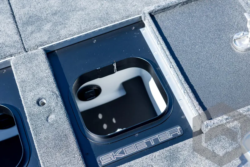 Slide: The Image of 2026 Skeeter FXR21 Apex boat storage compartment with carpeted deck. - 84