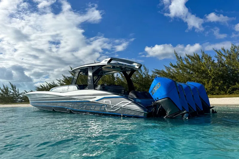 Slide: The Image of 2022 MTI V50 boat with blue engines on clear water near a sandy beach. - 1