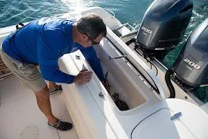 Slide: The Image of Man inspecting storage on 2026 Grady-White Freedom 275 boat with twin engines. - 9