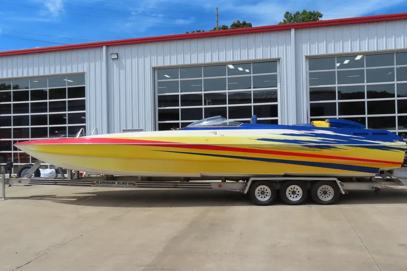 The Image of 2003 Spectre 36 Cat powerboat with vibrant yellow and blue design on a trailer. - 0