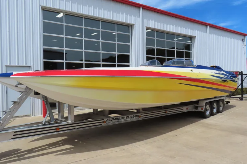 Slide: The Image of 2003 Spectre 36 Cat powerboat with vibrant yellow and red design on a trailer. - 1