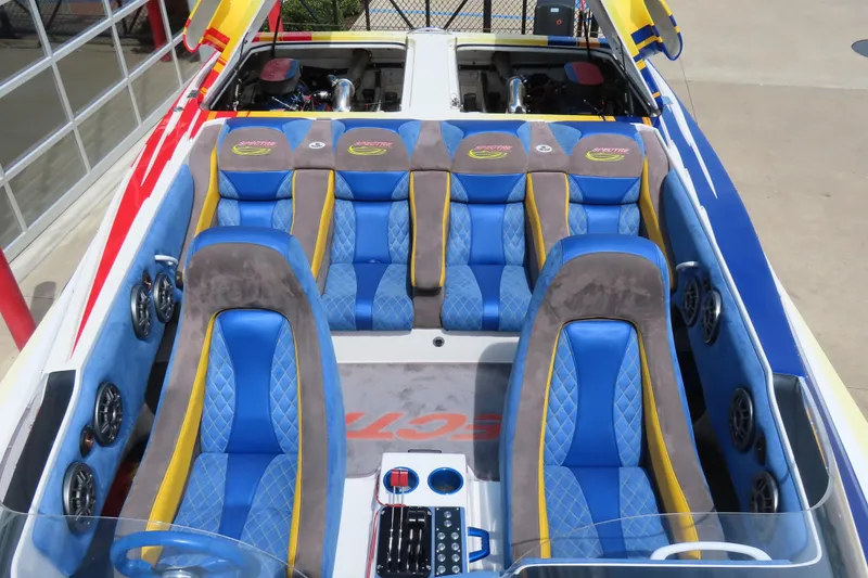 Slide: The Image of 2003 Spectre 36 Cat boat interior with blue and yellow seating, visible engine compartment. - 19