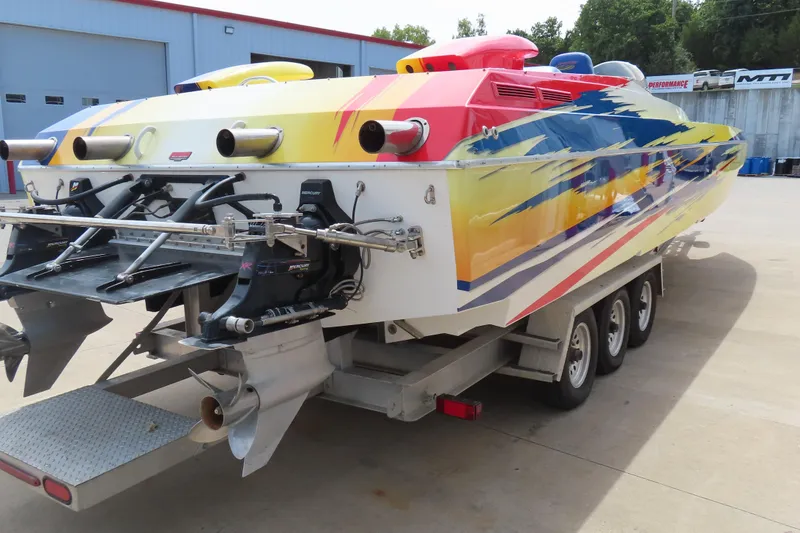 Slide: The Image of 2003 Spectre 36 Cat powerboat with vibrant paint, triple-axle trailer, and dual Mercury outboard engines. - 23