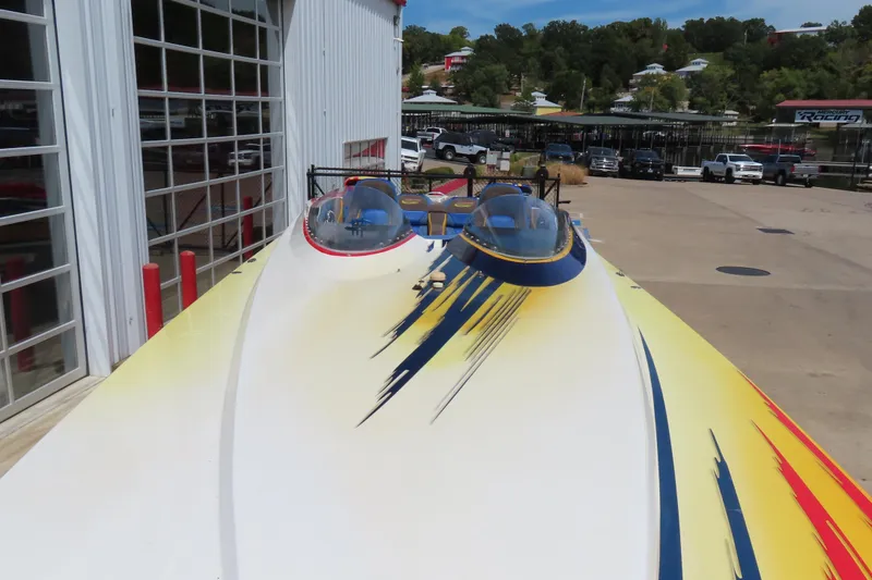 Slide: The Image of 2003 Spectre 36 Cat powerboat with vibrant yellow and blue design, docked near a marina. - 7