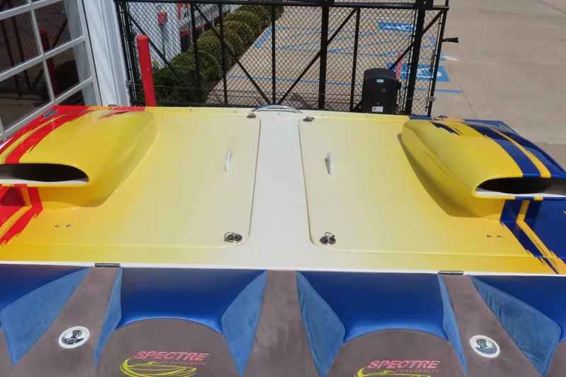 Slide: The Image of 2003 Spectre 36 Cat boat with vibrant yellow and blue design, docked near a fence. - 9