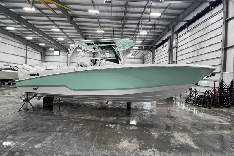Slide: The Image of 2026 Wellcraft 302 Fisherman boat in a spacious indoor storage facility. - 0
