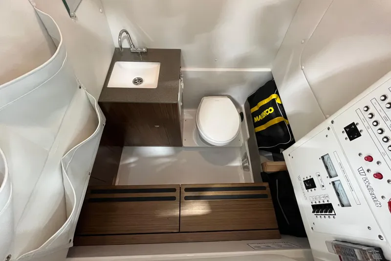 Slide: The Image of Interior of 2026 Wellcraft 302 Fisherman boat featuring a compact bathroom with sink and toilet. - 24