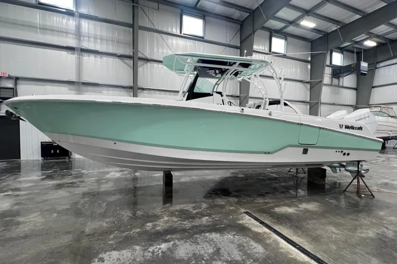 Slide: The Image of 2026 Wellcraft 302 Fisherman boat in a spacious indoor showroom. - 4