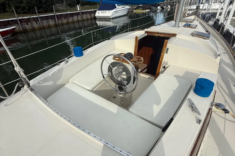 Slide: The Image of 1977 Irwin 37 Mark III sailboat cockpit with steering wheel and seating, docked by the water. - 11