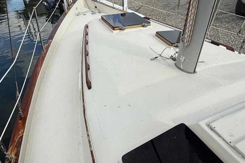 Slide: The Image of 1977 Irwin 37 Mark III sailboat deck with mast and hatches, docked by the water. - 20