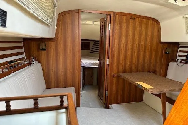 Slide: The Image of 1977 Irwin 37 Mark III yacht interior with wood paneling and cozy seating area. - 38