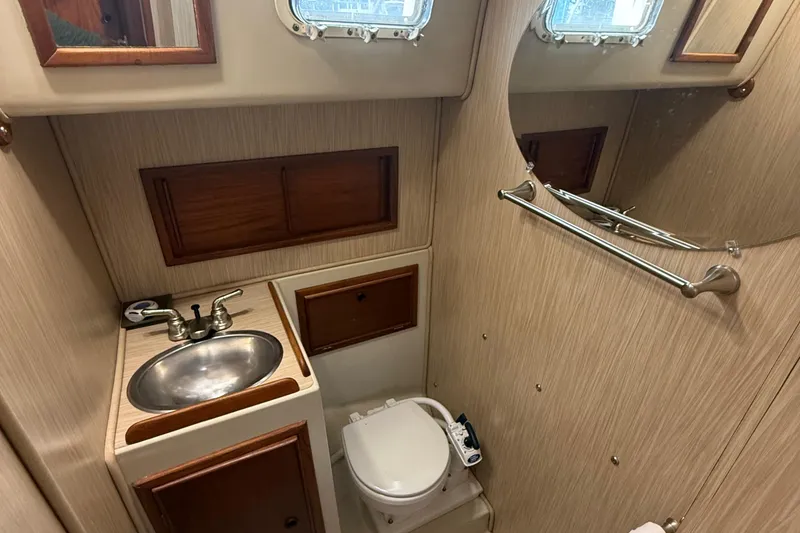 Slide: The Image of 1977 Irwin 37 Mark III yacht bathroom with sink, toilet, mirror, and wooden cabinets. - 54