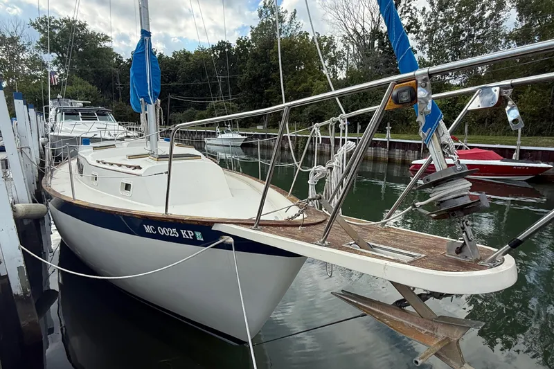 Slide: The Image of 1977 Irwin 37 Mark III sailboat docked in a marina, surrounded by trees. - 7