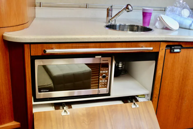 Slide: The Image of 2008 Tiara Yachts 3500 Sovran kitchen with microwave, sink, and wooden cabinetry. - 43