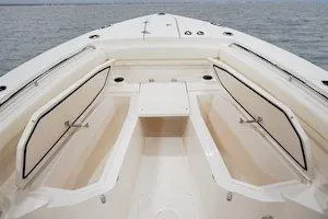 Slide: The Image of 2026 Grady-White Canyon 306 boat interior with open storage compartments on calm water. - 12