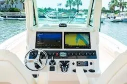 Slide: The Image of 2026 Grady-White Canyon 306 boat dashboard with dual navigation screens and steering wheel. - 9